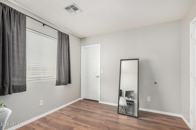 unfurnished bedroom with baseboards, visible vents, and wood finished floors