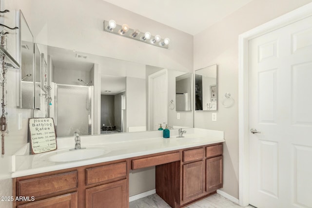 bathroom with marble finish floor, double vanity, a shower with shower door, and a sink