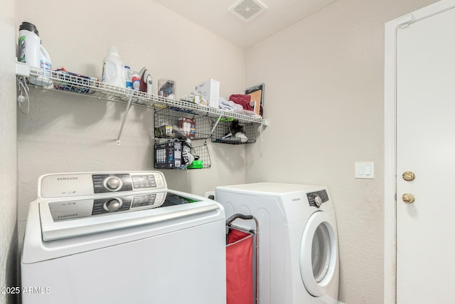 clothes washing area with washer and clothes dryer, laundry area, and visible vents