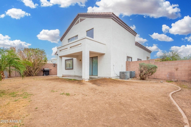 back of house featuring stucco siding, central AC unit, a fenced backyard, and a patio area
