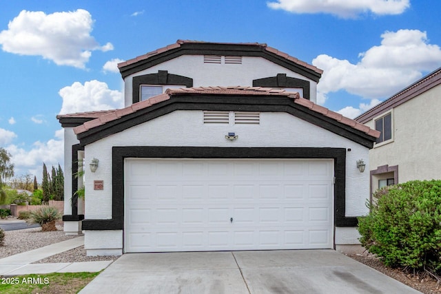 view of front of house with driveway, a garage, a tiled roof, and stucco siding