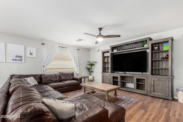 living area featuring a textured ceiling, visible vents, a ceiling fan, and wood finished floors