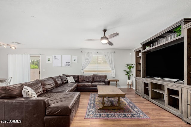 living area featuring light wood-style flooring, baseboards, a healthy amount of sunlight, and ceiling fan