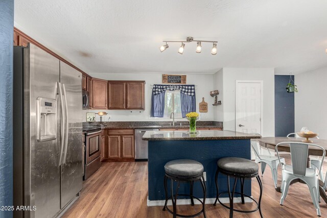 kitchen with a sink, stainless steel appliances, light wood-style floors, and a kitchen island