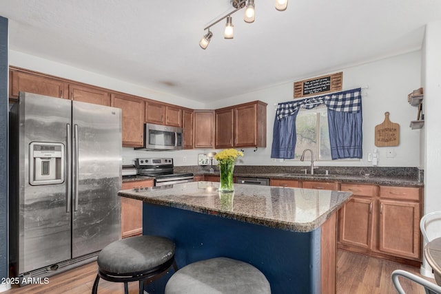 kitchen featuring light wood-style flooring, a sink, stainless steel appliances, and a kitchen island