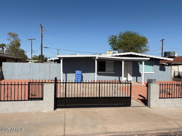 view of front of home featuring a fenced front yard, a gate, cooling unit, and stucco siding