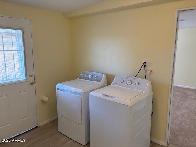 washroom with washer and clothes dryer, baseboards, and light wood-style flooring