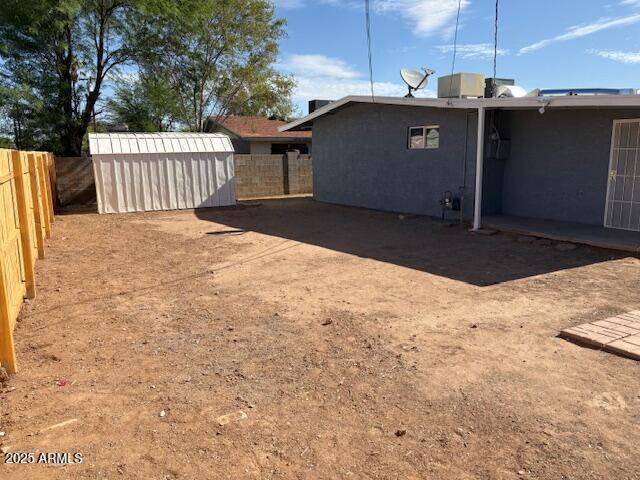 fenced backyard with an outdoor structure and a storage shed
