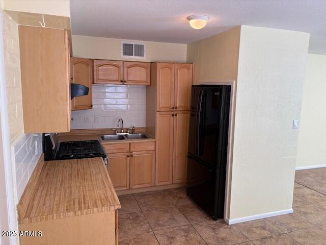 kitchen with freestanding refrigerator, a sink, range with gas cooktop, tasteful backsplash, and light countertops
