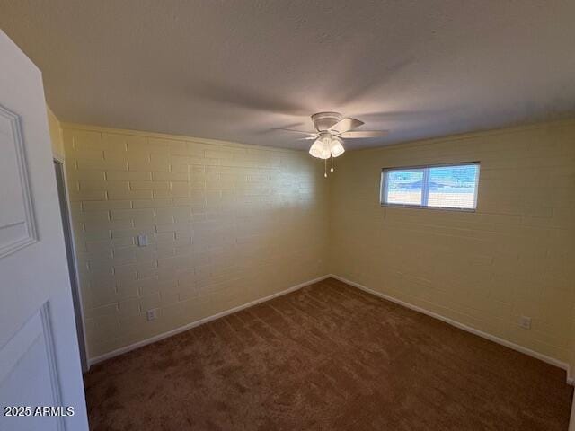 spare room featuring dark carpet, ceiling fan, and baseboards