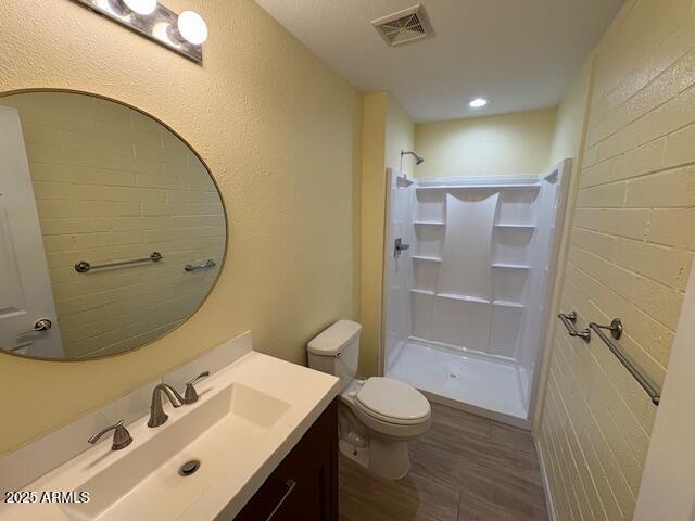 full bathroom featuring a walk in shower, toilet, wood finished floors, and vanity