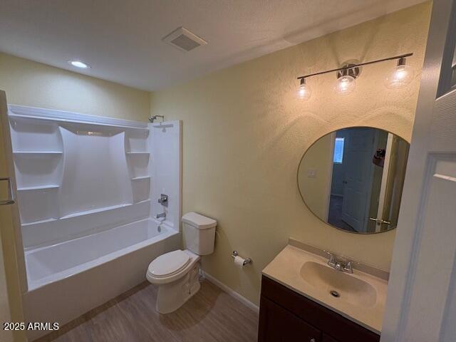full bath with toilet, wood finished floors, washtub / shower combination, vanity, and baseboards