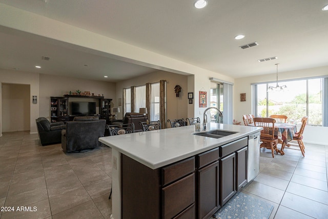 kitchen with a center island with sink, decorative light fixtures, sink, and dark brown cabinets