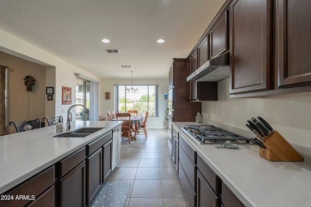 kitchen with dark brown cabinetry, light tile patterned floors, sink, decorative light fixtures, and stainless steel appliances