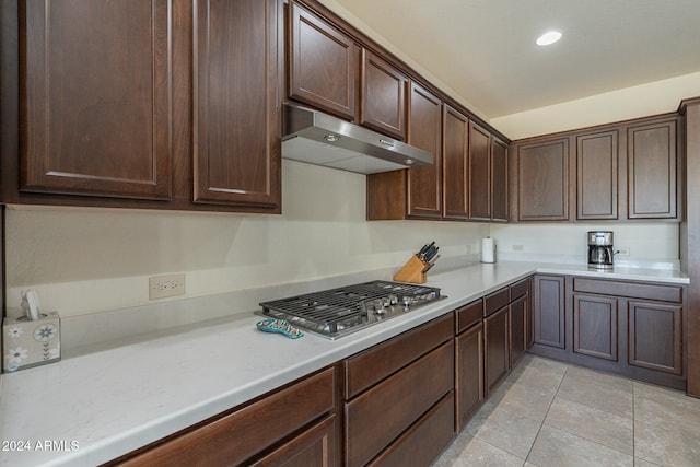 kitchen with stainless steel gas stovetop, light tile patterned flooring, and dark brown cabinets