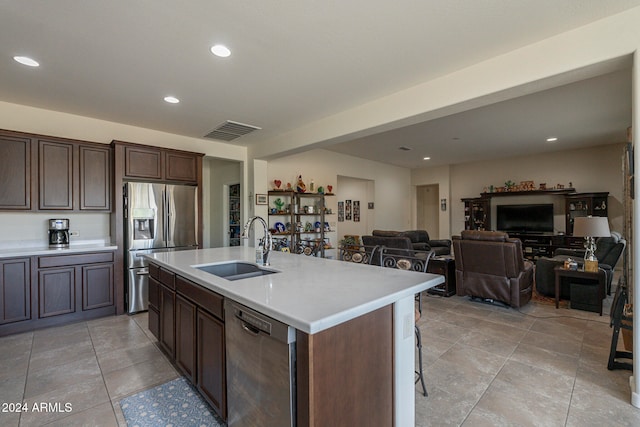 kitchen featuring a kitchen island with sink, a breakfast bar area, dark brown cabinetry, sink, and appliances with stainless steel finishes