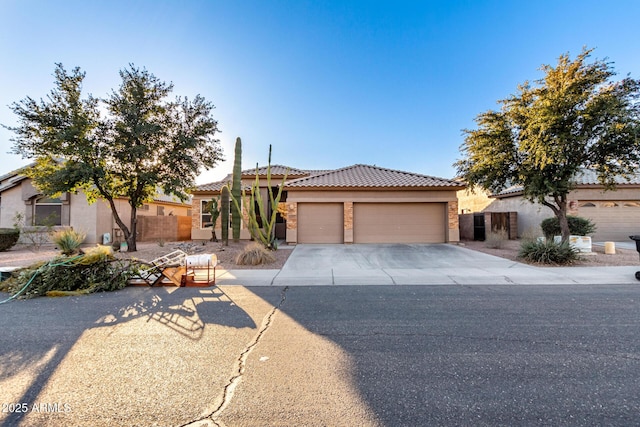 view of front of house featuring a garage, fence, a tile roof, driveway, and stucco siding