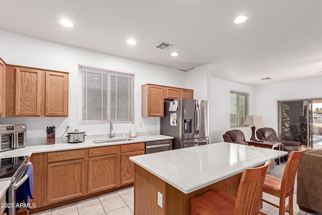 kitchen with a breakfast bar area, a sink, visible vents, open floor plan, and appliances with stainless steel finishes