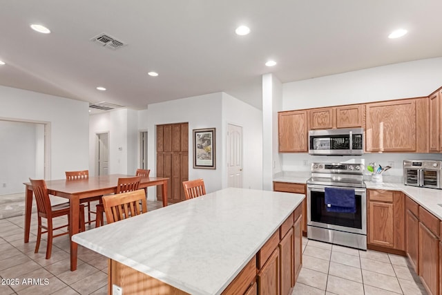 kitchen featuring light tile patterned floors, stainless steel appliances, light countertops, visible vents, and a kitchen island