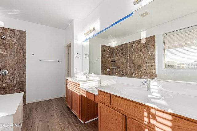 bathroom featuring double vanity, visible vents, a shower, wood finished floors, and a sink