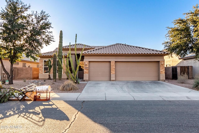 view of front of house featuring concrete driveway, a tile roof, an attached garage, fence, and stucco siding