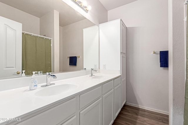 bathroom featuring double vanity, baseboards, a sink, and wood finished floors