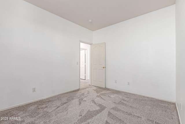 spare room featuring carpet flooring and baseboards