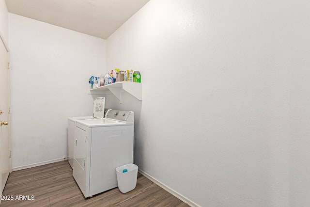 washroom with laundry area, washer and clothes dryer, light wood-style flooring, and baseboards