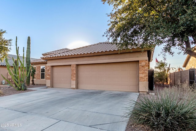 view of front facade featuring stucco siding, concrete driveway, an attached garage, fence, and a tiled roof