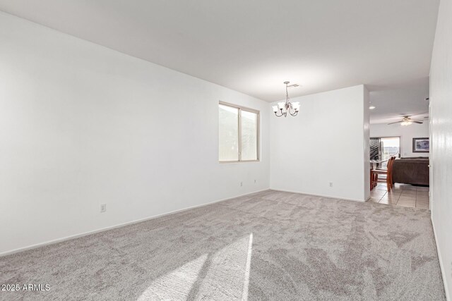 carpeted spare room featuring an inviting chandelier