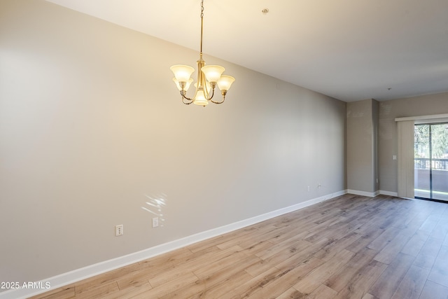 unfurnished room featuring a chandelier and light hardwood / wood-style flooring