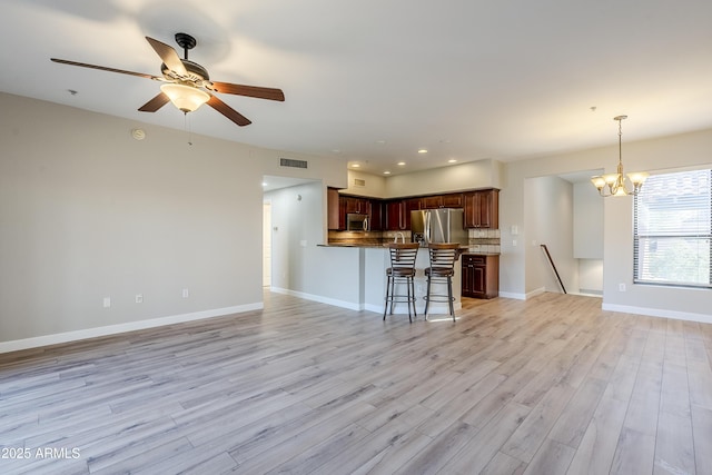 kitchen featuring a kitchen bar, pendant lighting, light hardwood / wood-style flooring, and stainless steel appliances