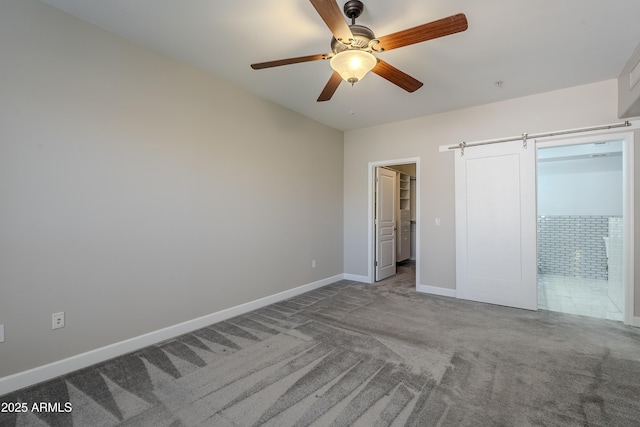 unfurnished bedroom featuring a walk in closet, ceiling fan, and carpet floors