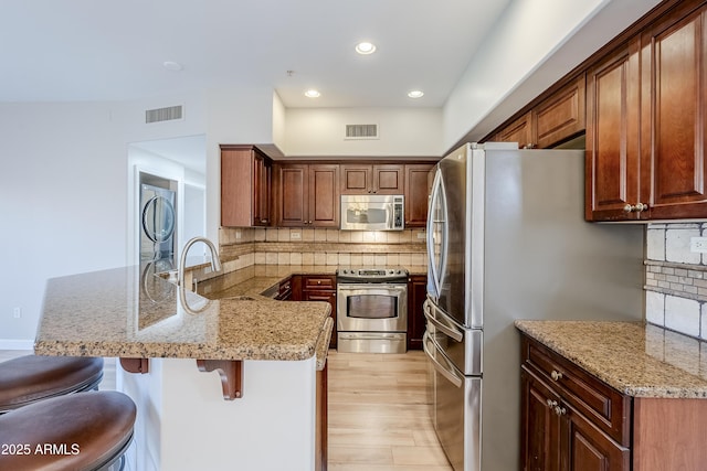 kitchen with a breakfast bar, stainless steel appliances, kitchen peninsula, and tasteful backsplash