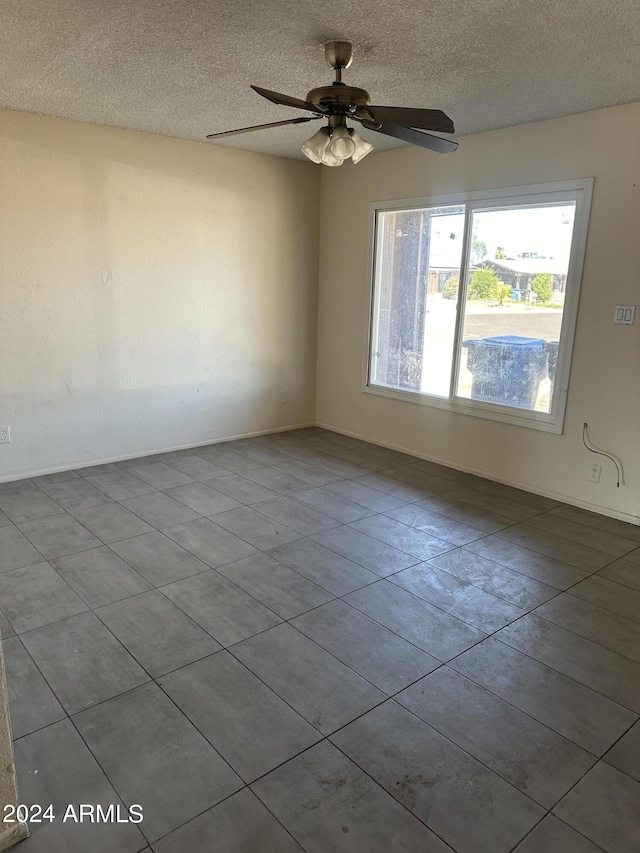 empty room with ceiling fan, a textured ceiling, and light tile patterned flooring