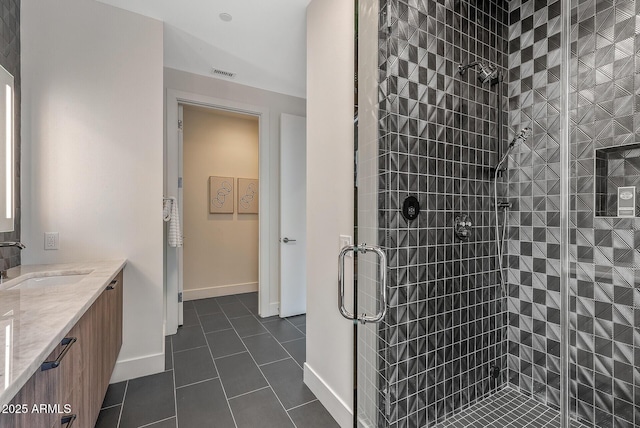 full bath featuring visible vents, a shower stall, tile patterned flooring, baseboards, and vanity