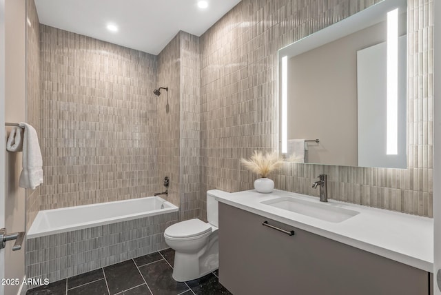 bathroom featuring vanity, tile walls, toilet, tiled shower / bath, and tile patterned floors