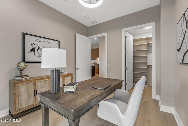 office space featuring light wood finished floors, visible vents, and baseboards