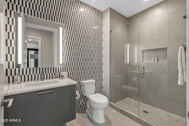 full bathroom with a shower stall, tile walls, toilet, tile patterned floors, and vanity