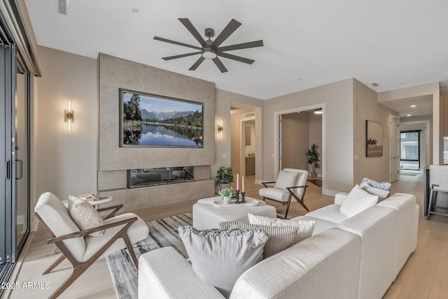 living room featuring visible vents, light wood-style flooring, ceiling fan, and a water view