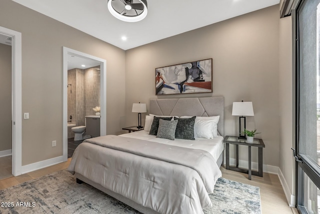 bedroom with baseboards, wood finished floors, and ensuite bathroom