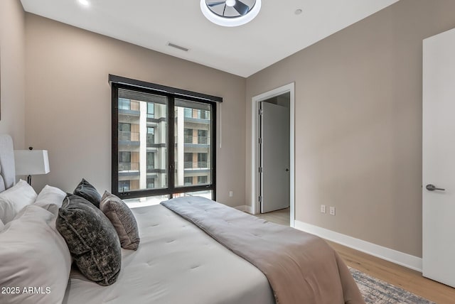 bedroom with visible vents, baseboards, light wood-style flooring, and access to outside