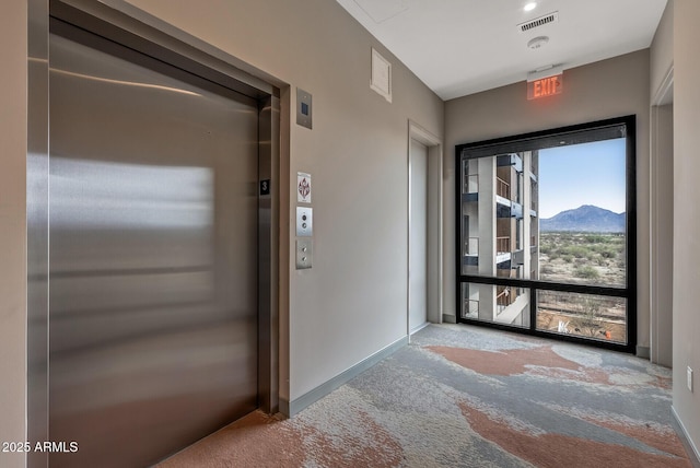 hallway featuring a mountain view, elevator, baseboards, and visible vents