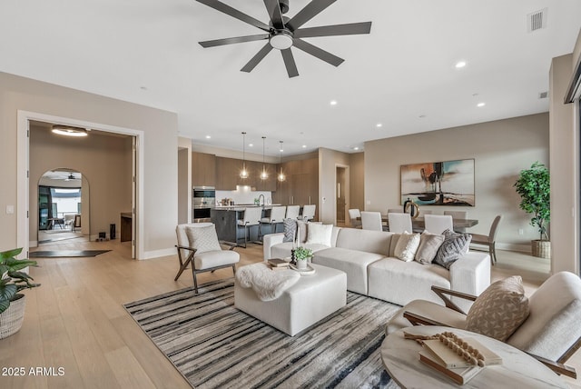 living room with a ceiling fan, visible vents, baseboards, recessed lighting, and light wood-type flooring