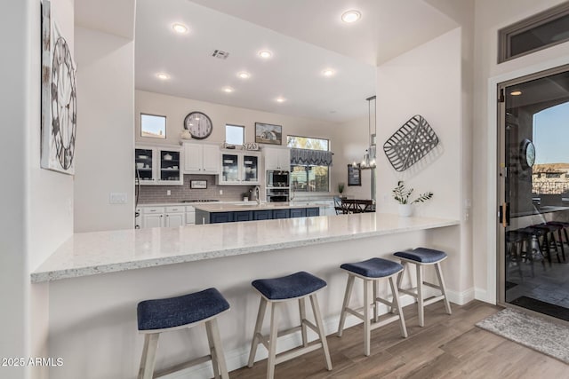 kitchen featuring stainless steel appliances, a peninsula, wood finished floors, and visible vents
