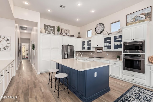kitchen featuring appliances with stainless steel finishes, a sink, visible vents, and light wood-type flooring
