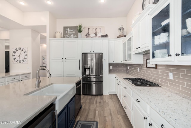kitchen featuring white cabinets, appliances with stainless steel finishes, light wood-style flooring, and tasteful backsplash