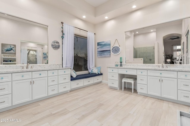 full bath with a sink, recessed lighting, two vanities, wood finished floors, and a stall shower