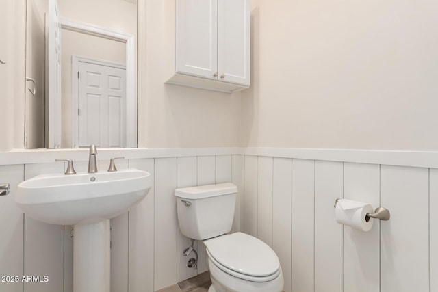 bathroom featuring toilet and wainscoting