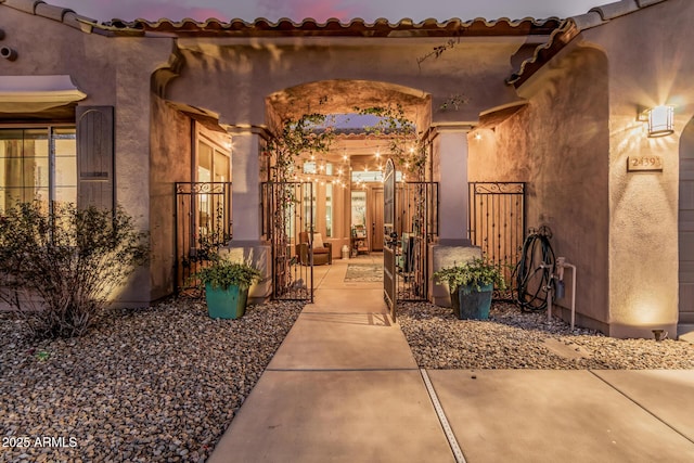 entrance to property featuring a gate and stucco siding